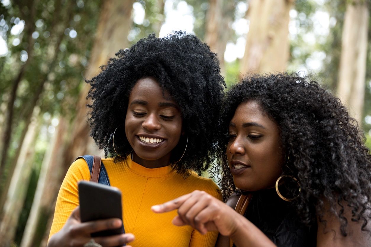 two black women looking at a cell phone